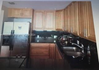 kitchen with light brown cabinetry, sink, and stainless steel fridge