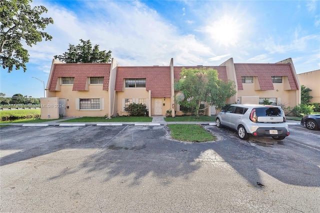 34 Meacham Ln, Tamarac, FL 33319 - view of front of house with uncovered parking, mansard roof, and stucco siding