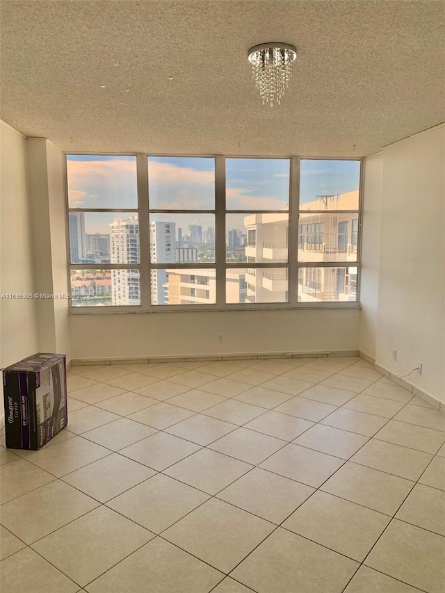 unfurnished room with a notable chandelier, a textured ceiling, and light tile patterned floors