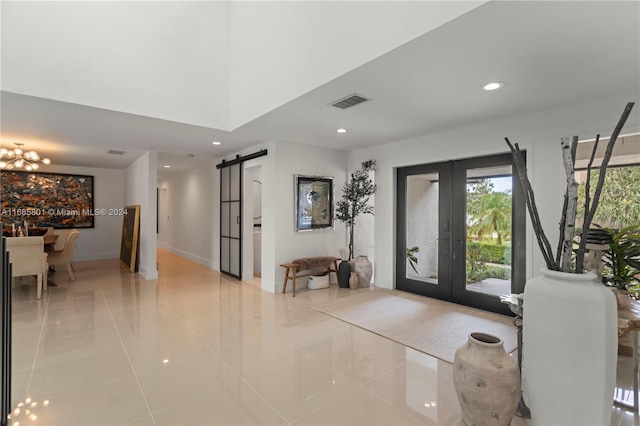 entrance foyer featuring french doors, an inviting chandelier, a barn door, and light tile patterned flooring