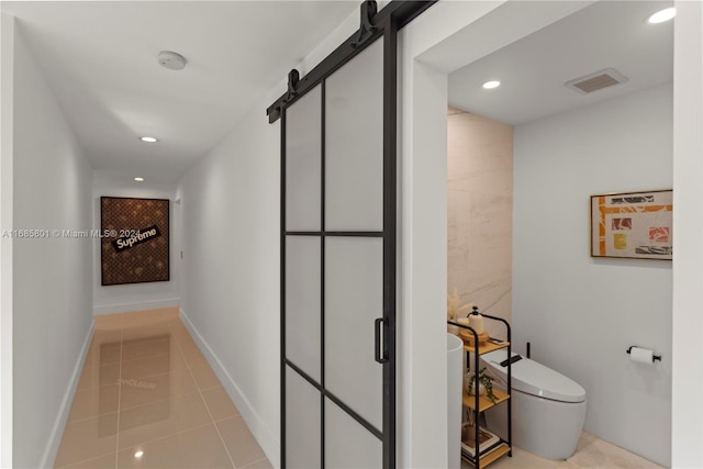 corridor with a barn door and light tile patterned flooring