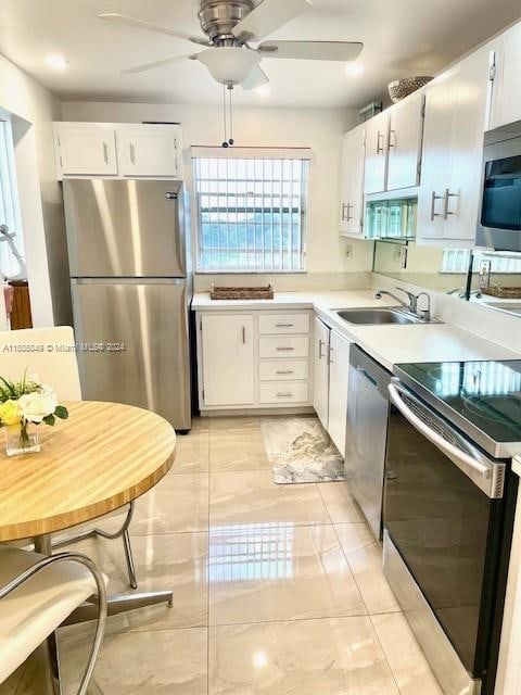 kitchen with white cabinets, appliances with stainless steel finishes, sink, and ceiling fan