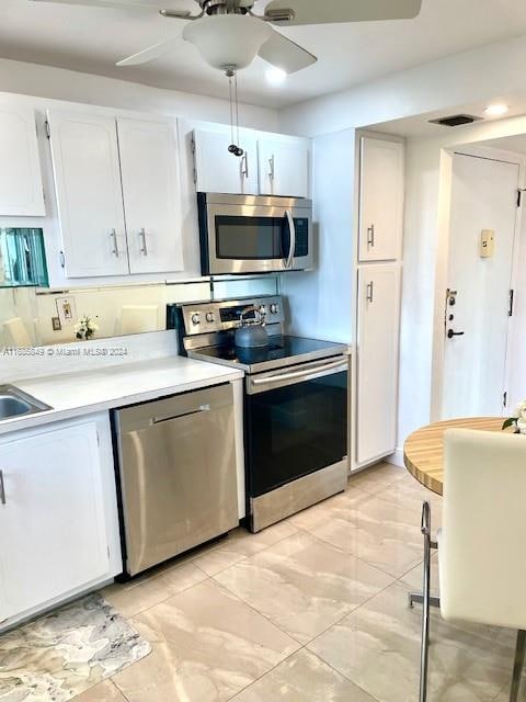 kitchen featuring tasteful backsplash, white cabinetry, appliances with stainless steel finishes, and ceiling fan