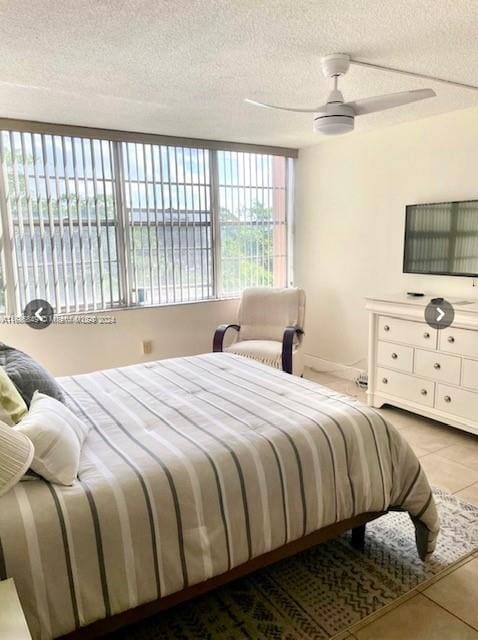 bedroom featuring light tile patterned flooring, ceiling fan, and a textured ceiling