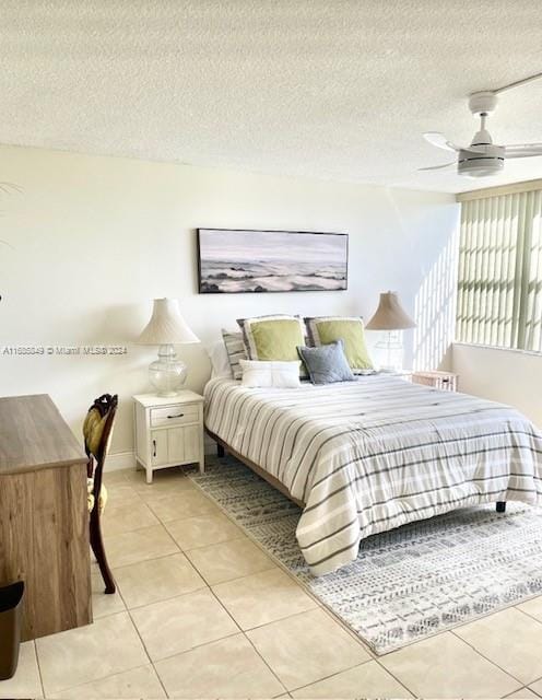 bedroom with a textured ceiling, ceiling fan, and light tile patterned flooring