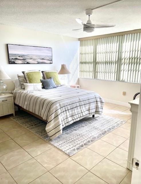 bedroom with a textured ceiling, ceiling fan, and light tile patterned floors