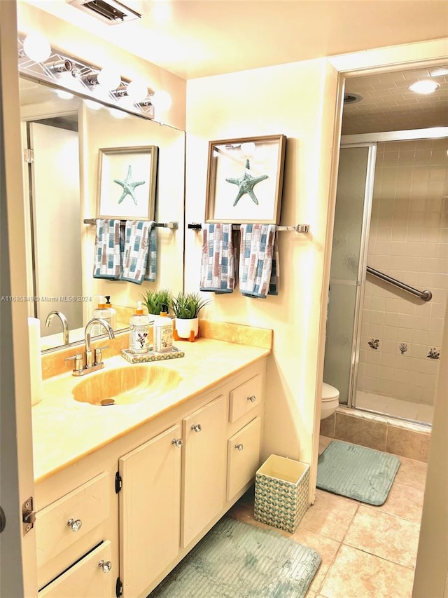 bathroom featuring toilet, vanity, tile patterned floors, and a shower with shower door