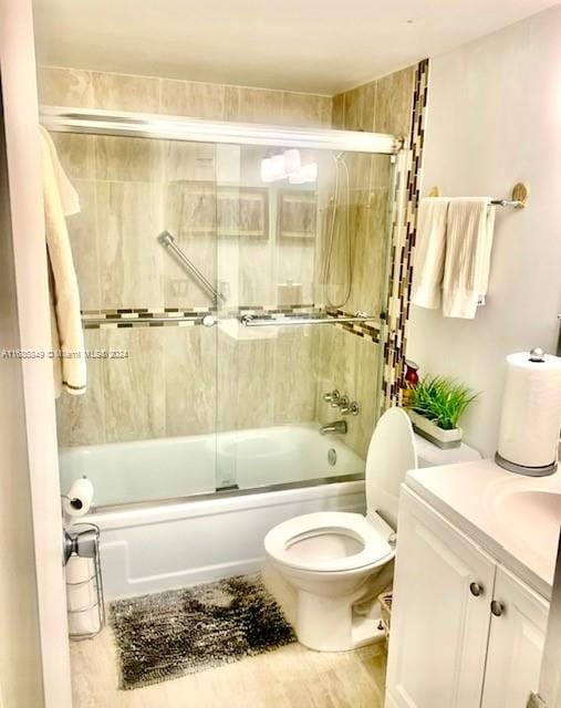 full bathroom with enclosed tub / shower combo, toilet, and vanity