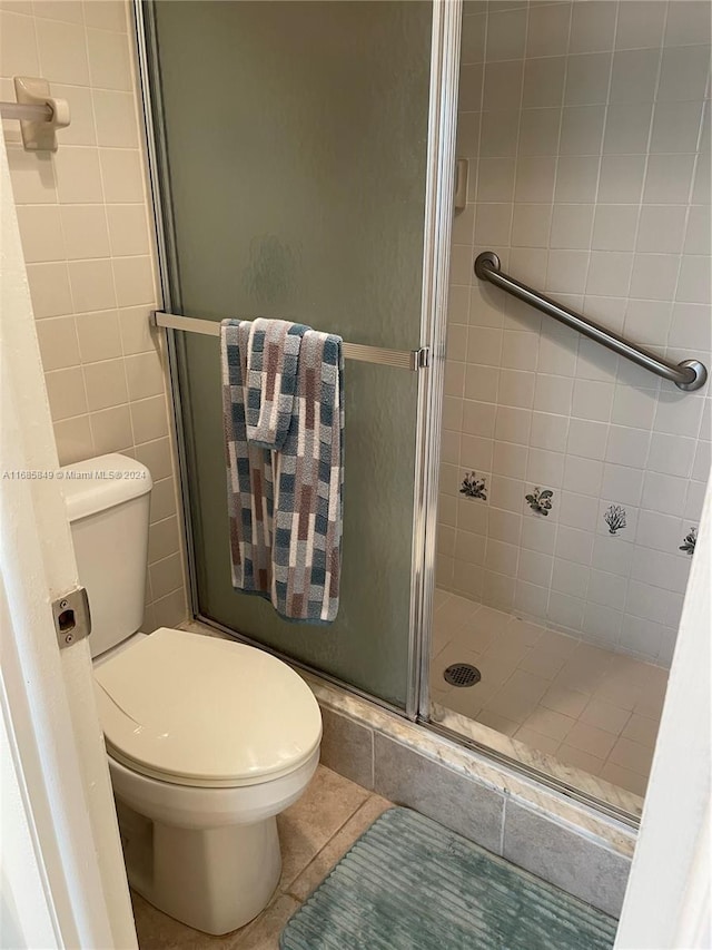 bathroom with toilet, tile patterned flooring, and a shower with shower door