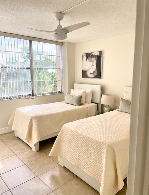 tiled bedroom with a textured ceiling and ceiling fan