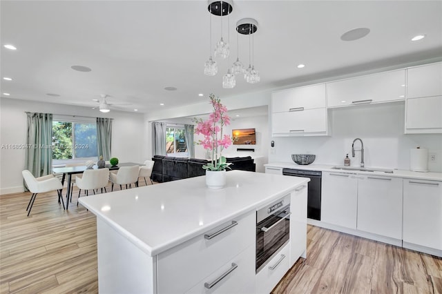 kitchen with dishwasher, sink, a center island, white cabinetry, and light hardwood / wood-style floors