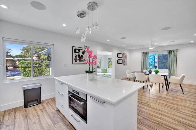 kitchen featuring light hardwood / wood-style floors, white cabinetry, a healthy amount of sunlight, and hanging light fixtures