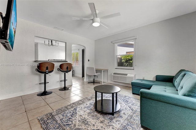 tiled living room with a wall unit AC and ceiling fan with notable chandelier