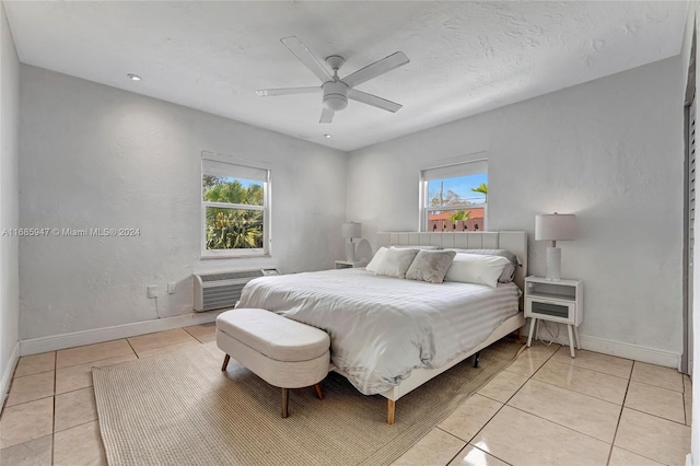 bedroom featuring an AC wall unit, multiple windows, light tile patterned floors, and ceiling fan