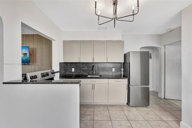 kitchen with sink, backsplash, stainless steel refrigerator, and dark stone counters