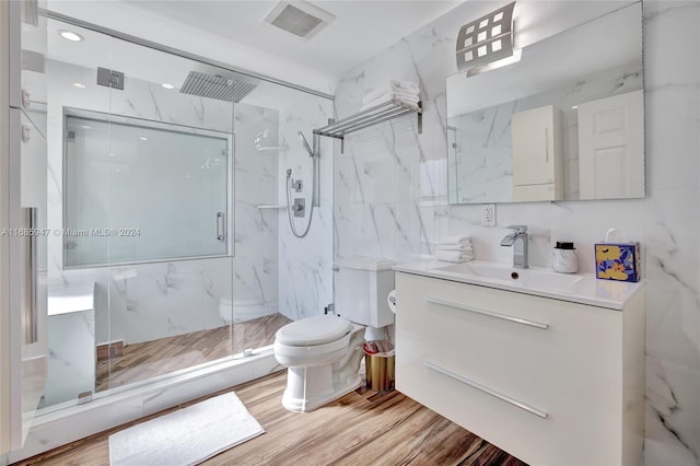 bathroom with toilet, hardwood / wood-style floors, a shower with shower door, and vanity