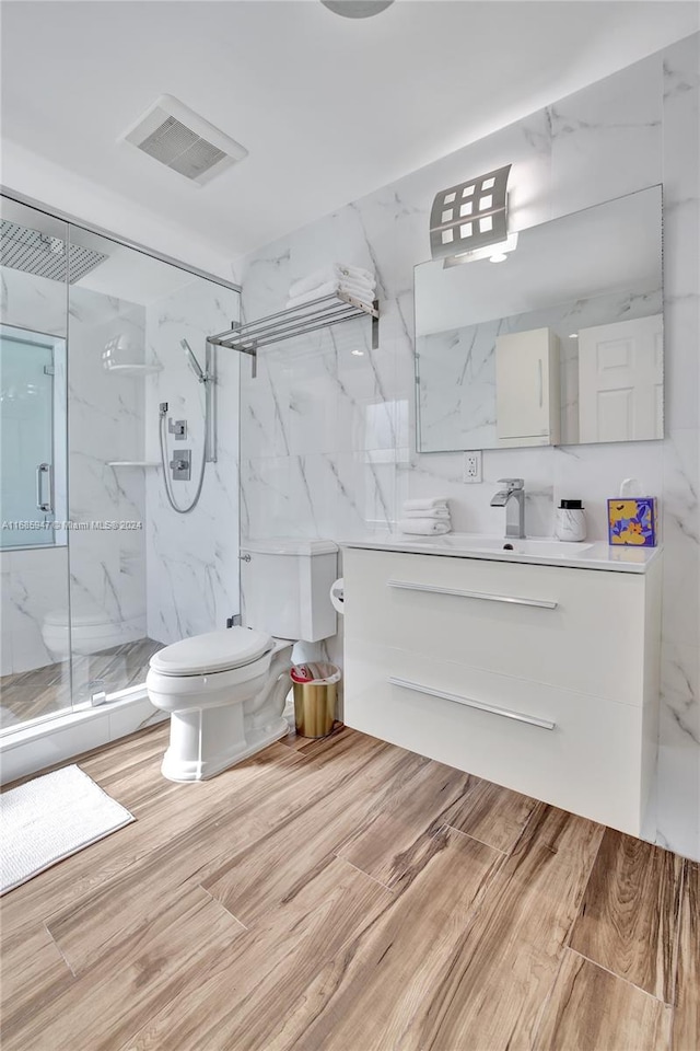 bathroom featuring vanity, hardwood / wood-style floors, toilet, and a shower with door