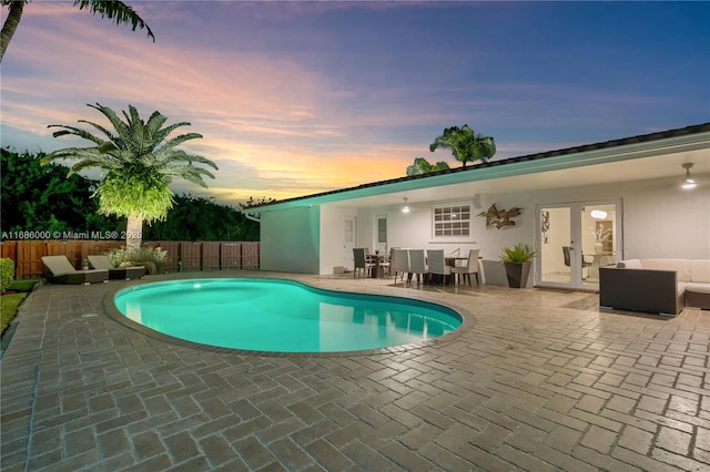 pool at dusk featuring an outdoor living space and a patio area