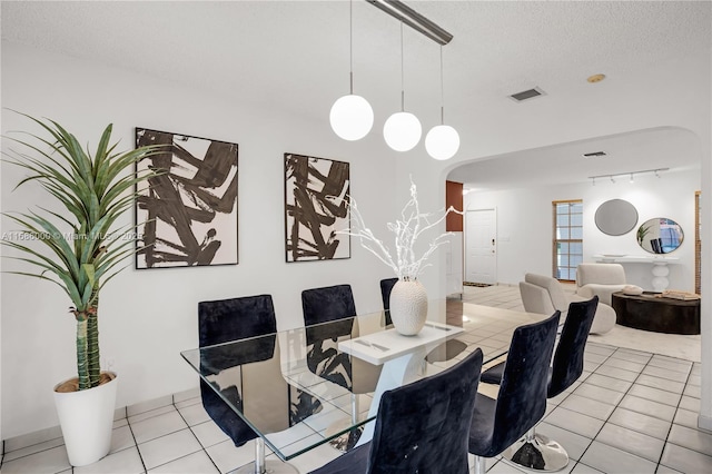 tiled dining area featuring track lighting and a textured ceiling