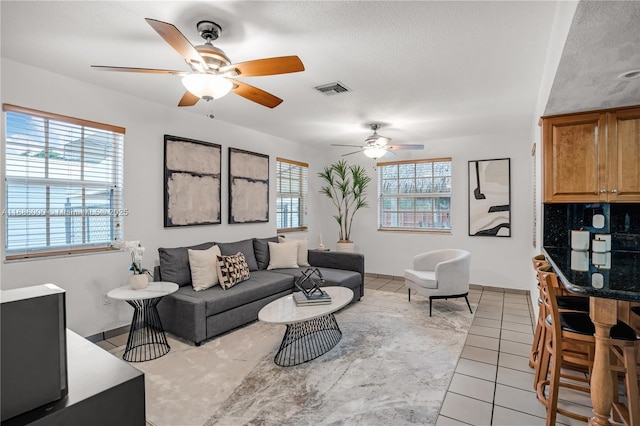 tiled living room featuring a textured ceiling and ceiling fan