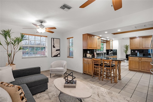 living room featuring sink, a wealth of natural light, ceiling fan, and light tile patterned flooring