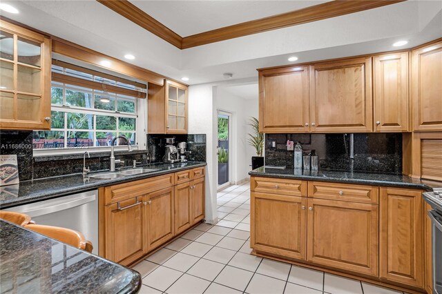 kitchen with dishwasher, light tile patterned floors, dark stone counters, ornamental molding, and sink