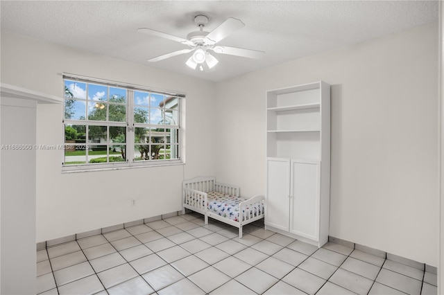 unfurnished bedroom with ceiling fan, a textured ceiling, and light tile patterned flooring