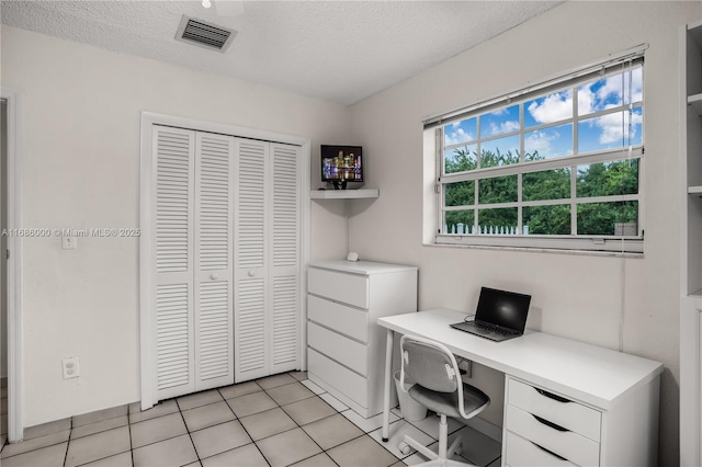 tiled bedroom featuring a textured ceiling, ceiling fan, and a closet