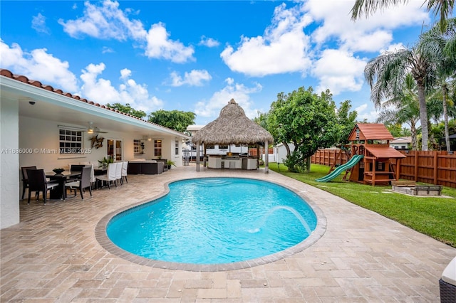 view of swimming pool featuring a playground, a patio, pool water feature, ceiling fan, and a gazebo