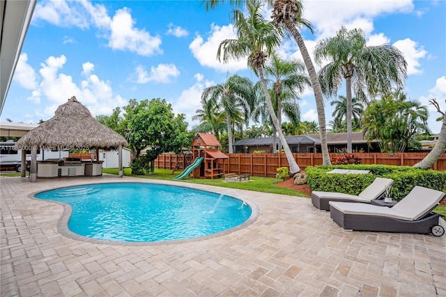 view of pool featuring a playground, a patio, area for grilling, pool water feature, and a gazebo