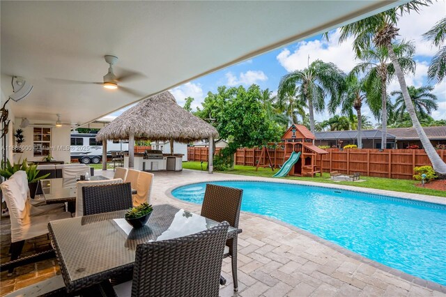 view of pool with a patio, a gazebo, exterior kitchen, a playground, and ceiling fan