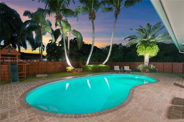 pool at dusk with a patio area and outdoor lounge area