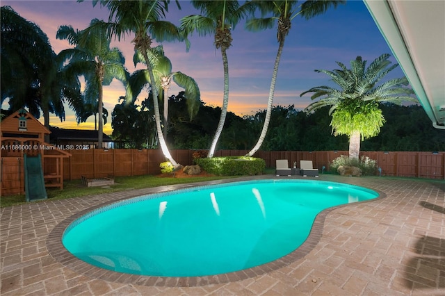 pool at dusk with a patio area