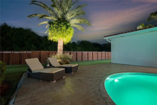 pool at dusk featuring a patio