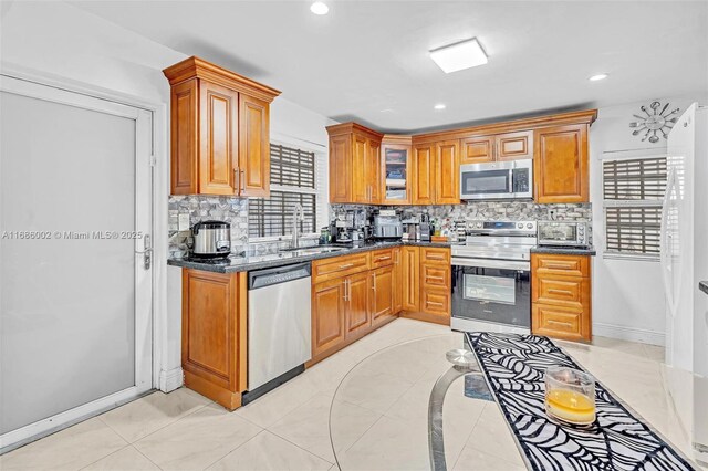 kitchen featuring sink, appliances with stainless steel finishes, dark stone countertops, and tasteful backsplash