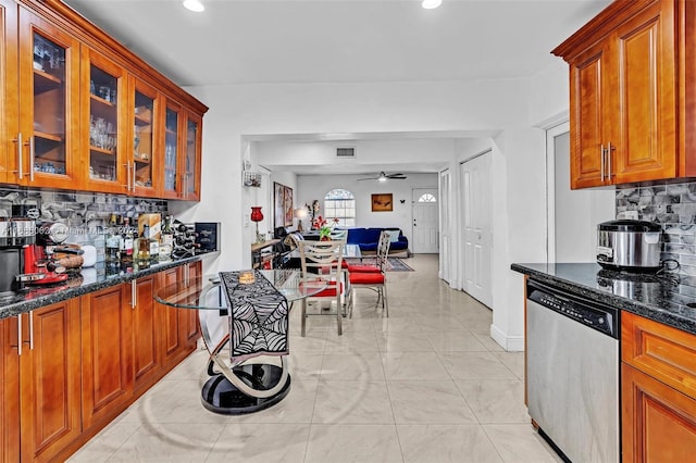 kitchen with stainless steel dishwasher, ceiling fan, dark stone counters, and tasteful backsplash