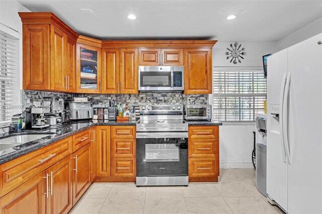 kitchen featuring dark stone countertops, appliances with stainless steel finishes, and decorative backsplash