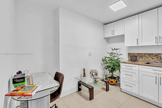 kitchen with sink, white cabinetry, light tile patterned floors, and dark stone countertops