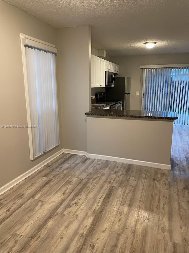 kitchen featuring white cabinets, kitchen peninsula, stainless steel appliances, and light wood-type flooring