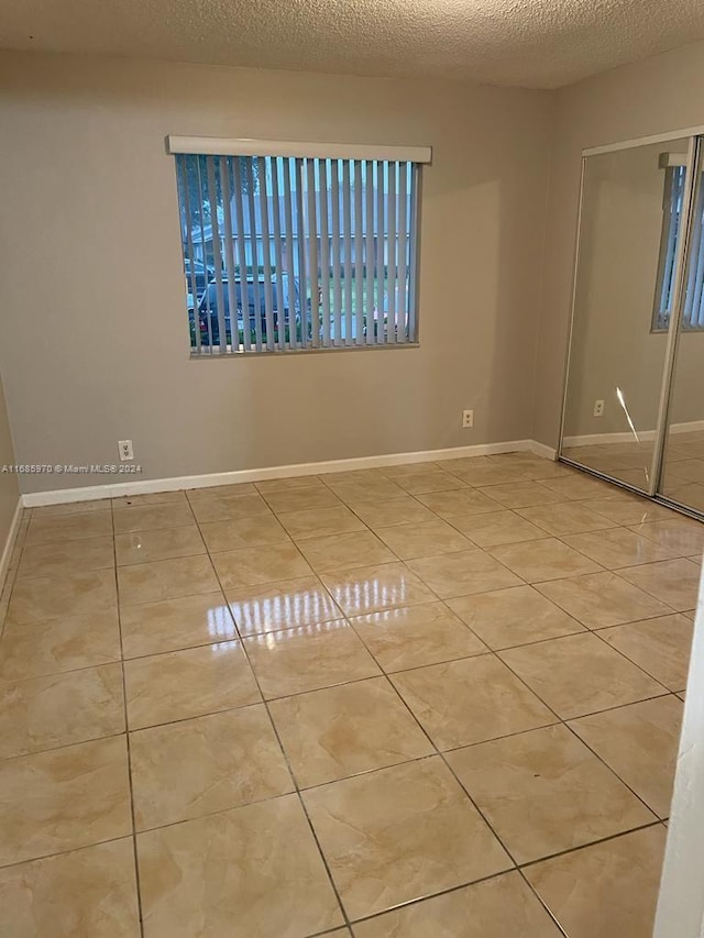 spare room featuring a textured ceiling and light tile patterned floors