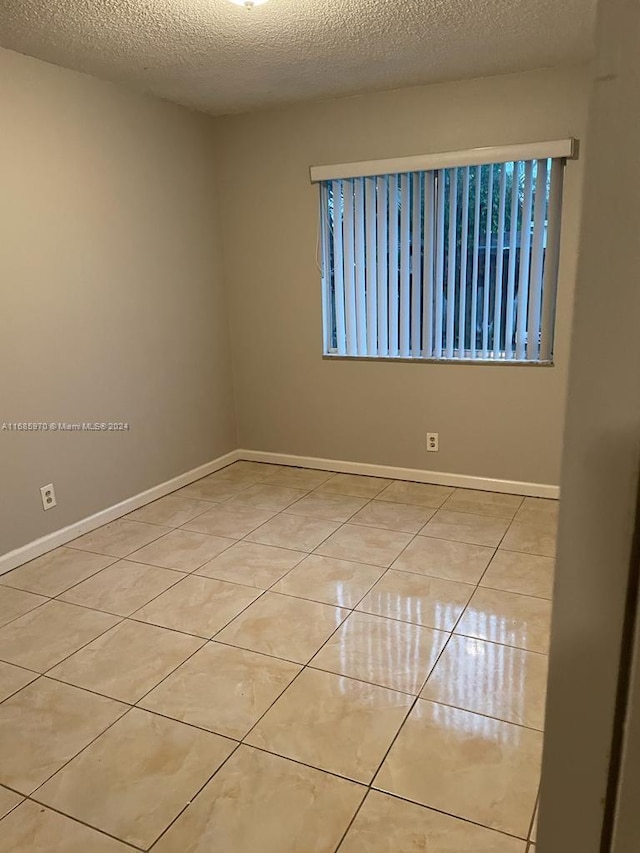 spare room featuring a textured ceiling and light tile patterned floors