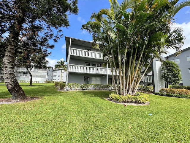 rear view of property with a yard and a balcony