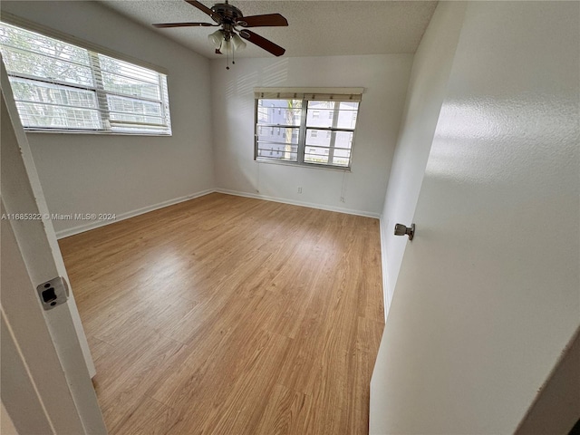 empty room featuring a textured ceiling, light hardwood / wood-style flooring, and ceiling fan