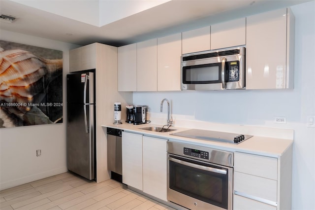 kitchen with white cabinets, light hardwood / wood-style floors, sink, and appliances with stainless steel finishes