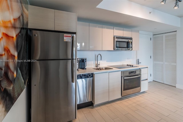 kitchen with stainless steel appliances, light hardwood / wood-style flooring, and sink