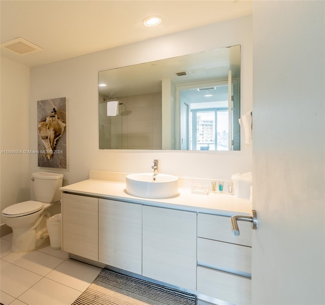 bathroom with tile patterned flooring, vanity, toilet, and tiled shower