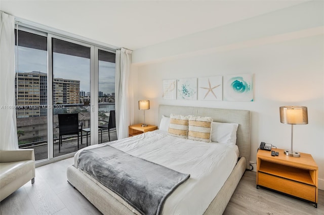 bedroom featuring light hardwood / wood-style floors, access to exterior, and floor to ceiling windows