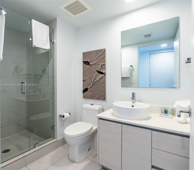 bathroom with tile patterned floors, a shower with door, vanity, and toilet