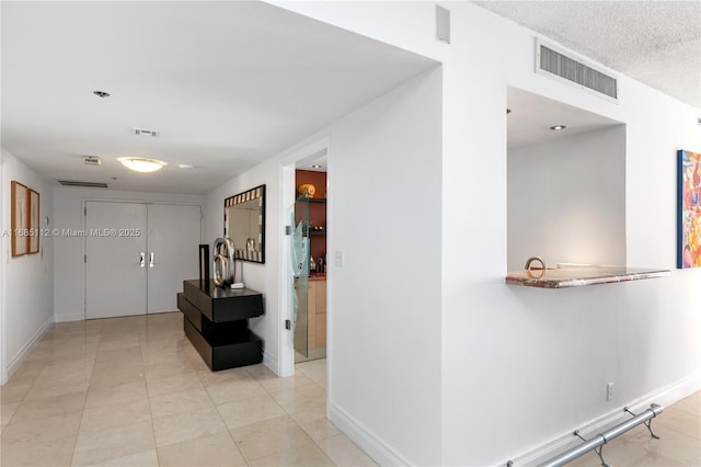 hall featuring light tile patterned flooring and a textured ceiling