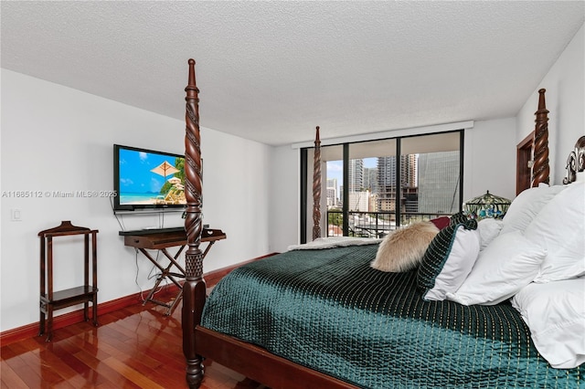 bedroom featuring access to outside, floor to ceiling windows, a textured ceiling, and hardwood / wood-style flooring